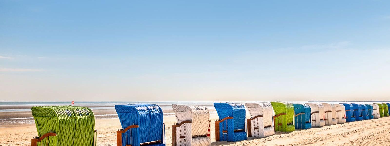 Bunte Strandkörbe im Sand auf der Nordseeinsel Föhr