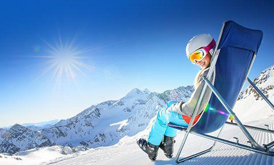 Mädchen in Ski-Ausrüstung mit Blick über verschneite Alpen