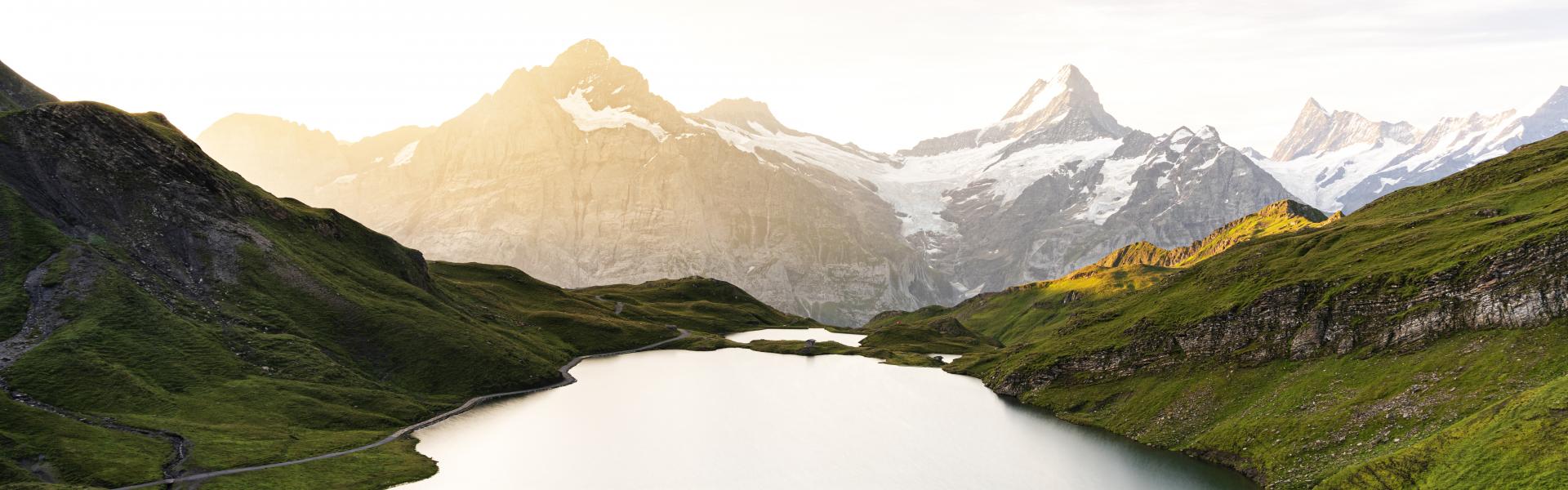High angle view of hiker man walking at Bachalpsee lake during a misty sunrise, Grindelwald, Bernese Oberland, Bern Canton, Switzerland
