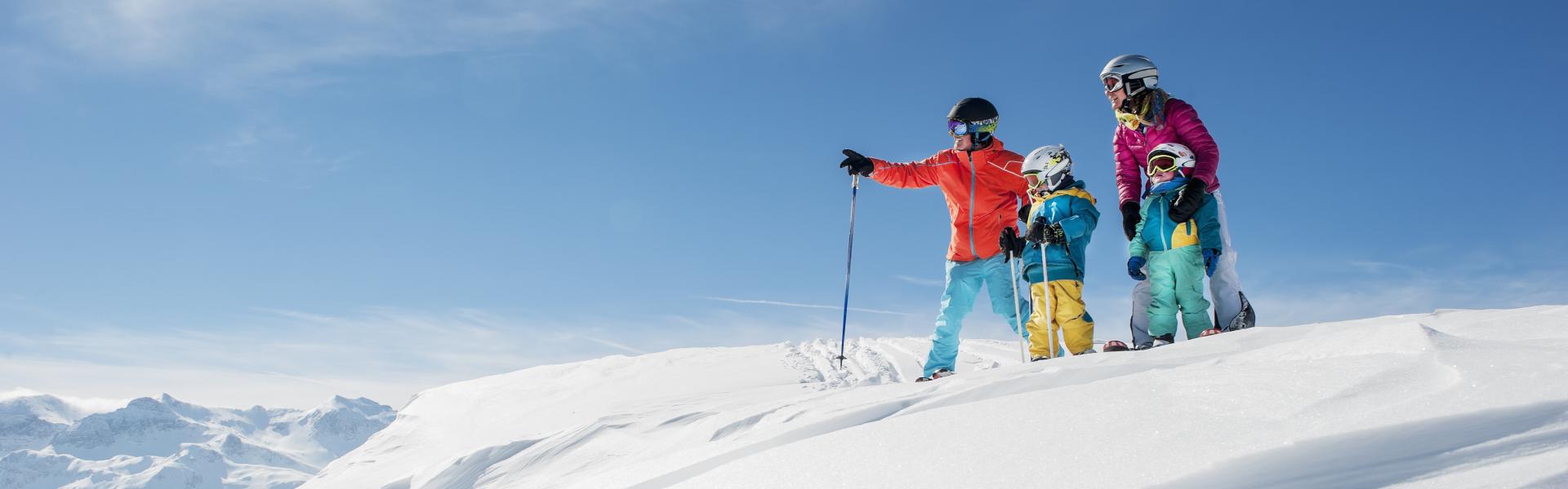 Mädchen in Ski-Ausrüstung mit Blick über verschneite Alpen