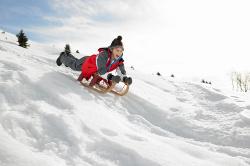 Junge auf Schlitten im Schneeurlaub